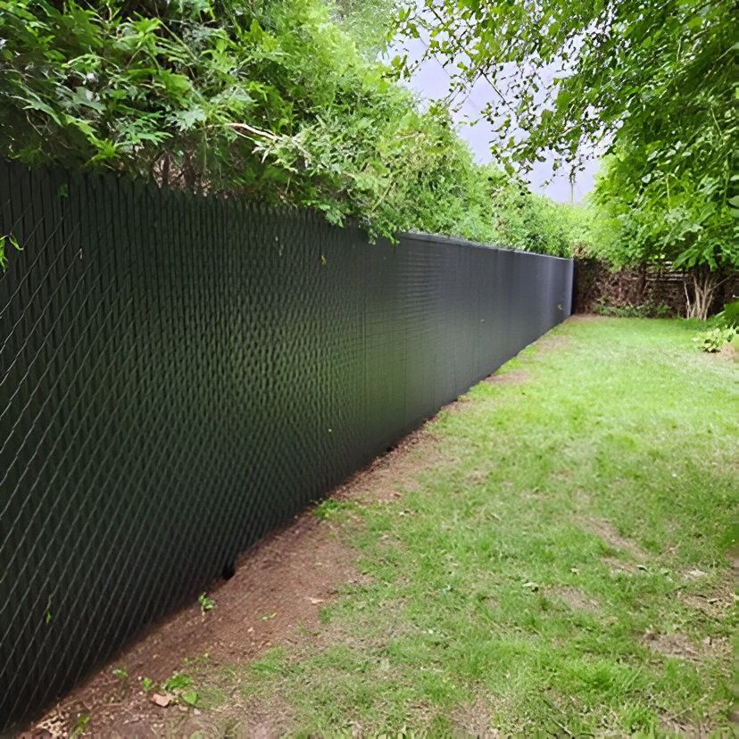 Black lattice fence alongside green grass and trees in a backyard setting.