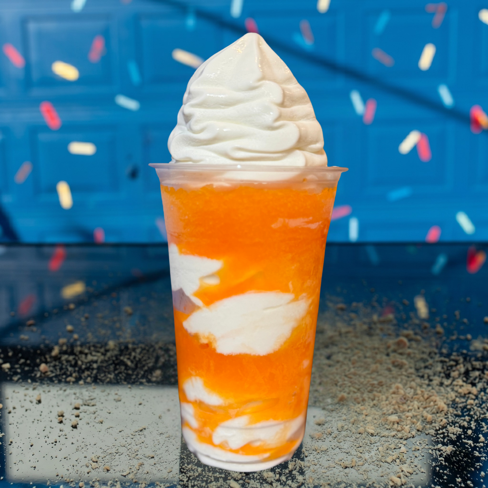 Orange-and-white layered dessert drink topped with whipped cream against a blue background