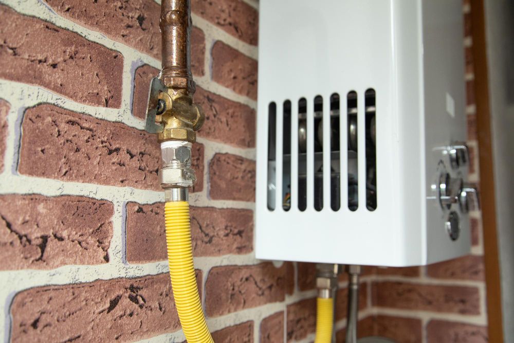 Yellow gas line connected to a wall-mounted white utility box beside a brick wall