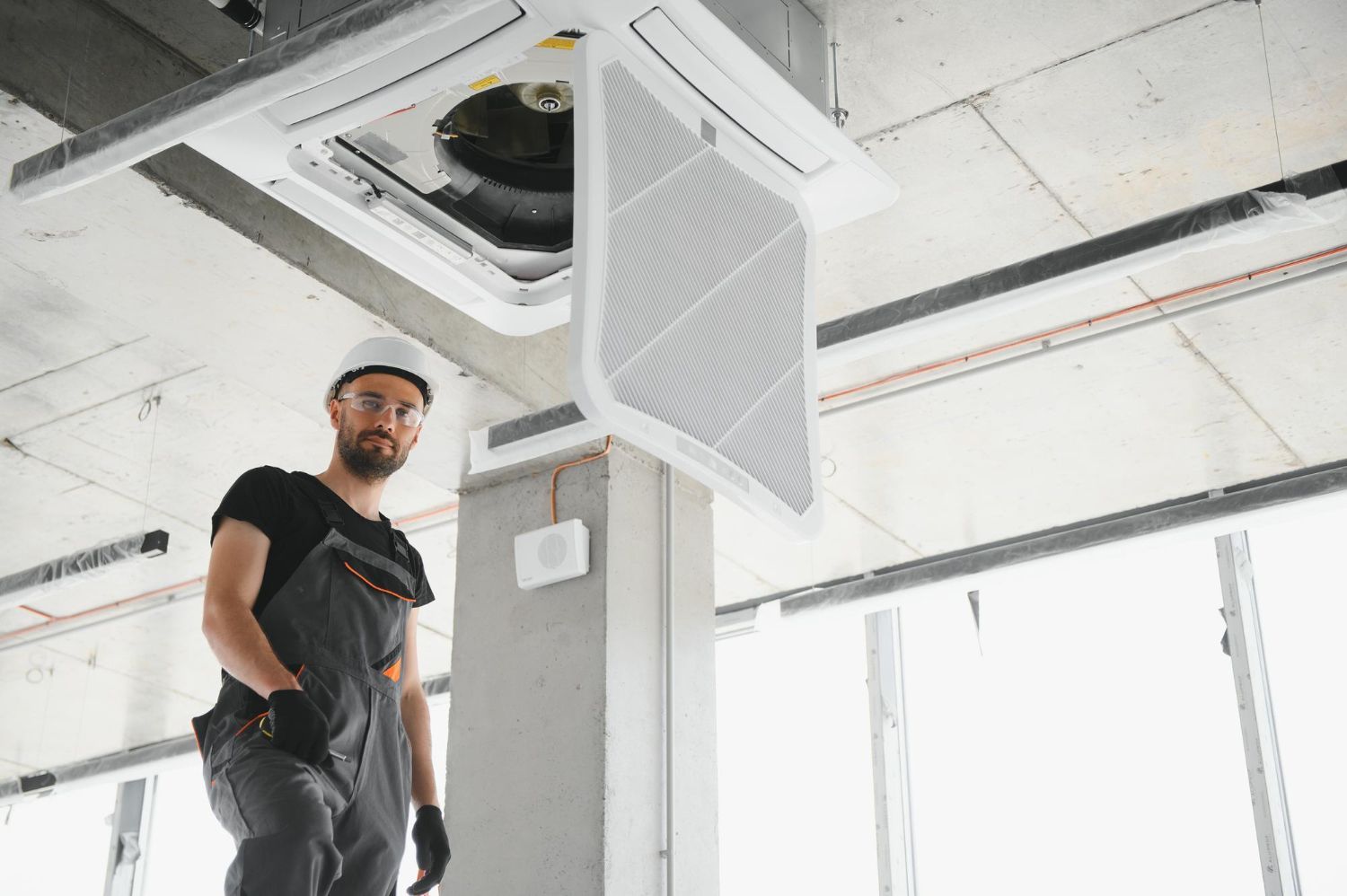 Man standing in a bright industrial room beneath an open ceiling vent