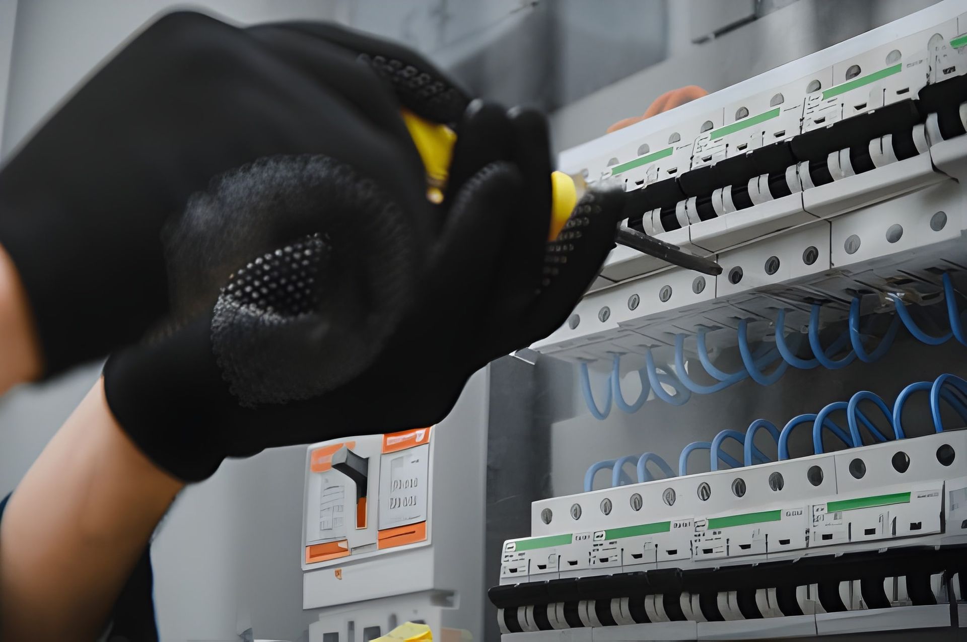Gloved hand adjusting circuit breakers in an electrical panel