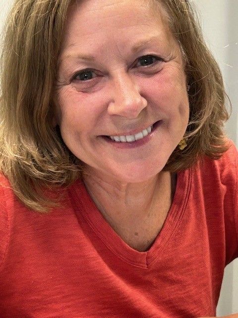 Woman with light brown hair and an orange shirt smiling, dimples showing. Woman with light brown hair and an orange shirt smiling, dimples showing.