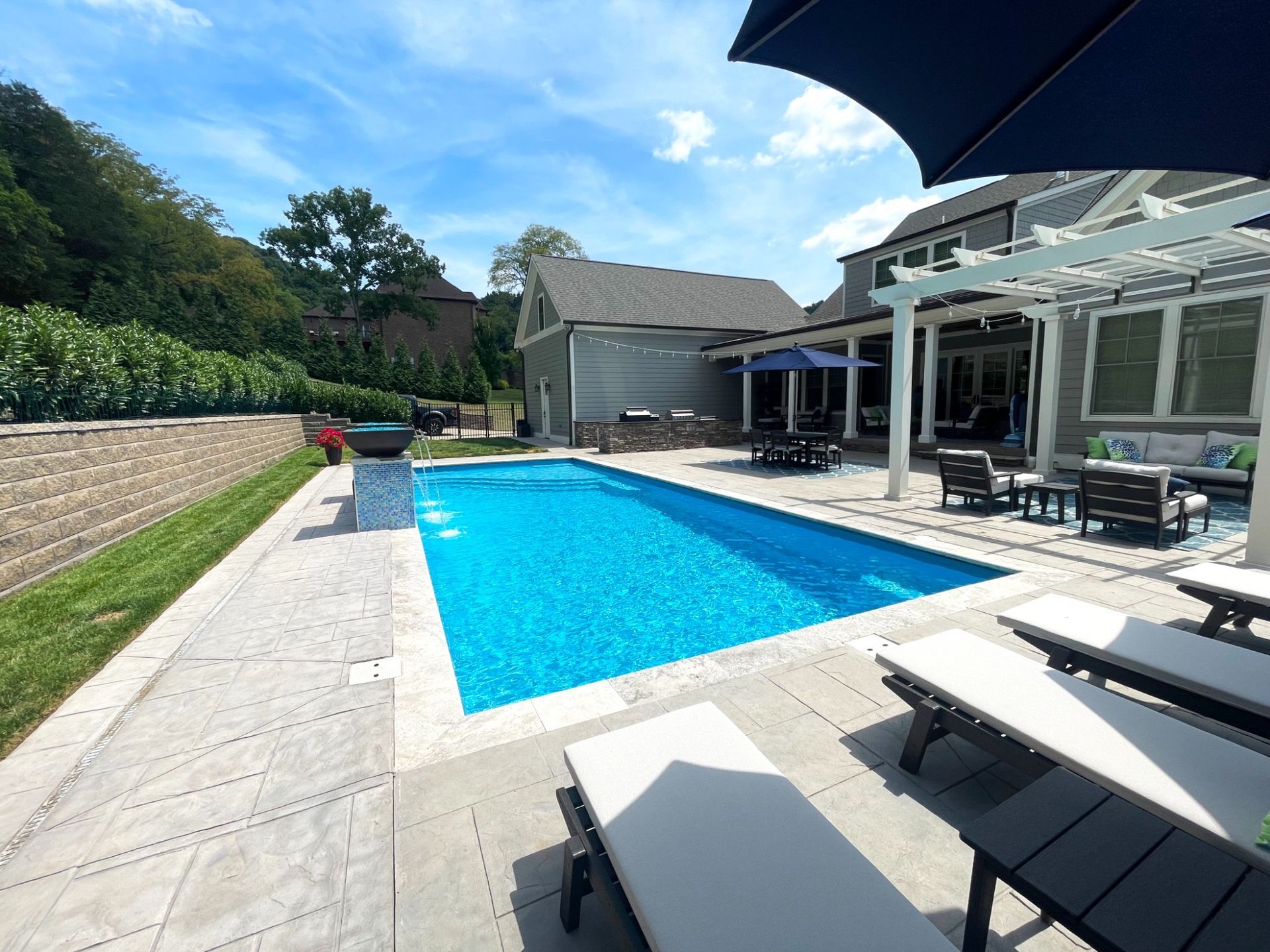 Side view of Majestic Swim custom pool project with stone patio and waterfall in Eagleville
