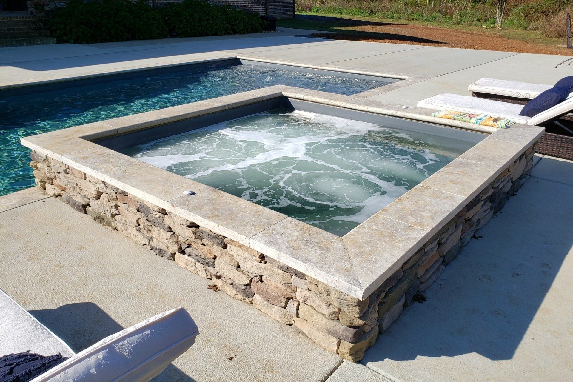 A hot tub is sitting next to a swimming pool.