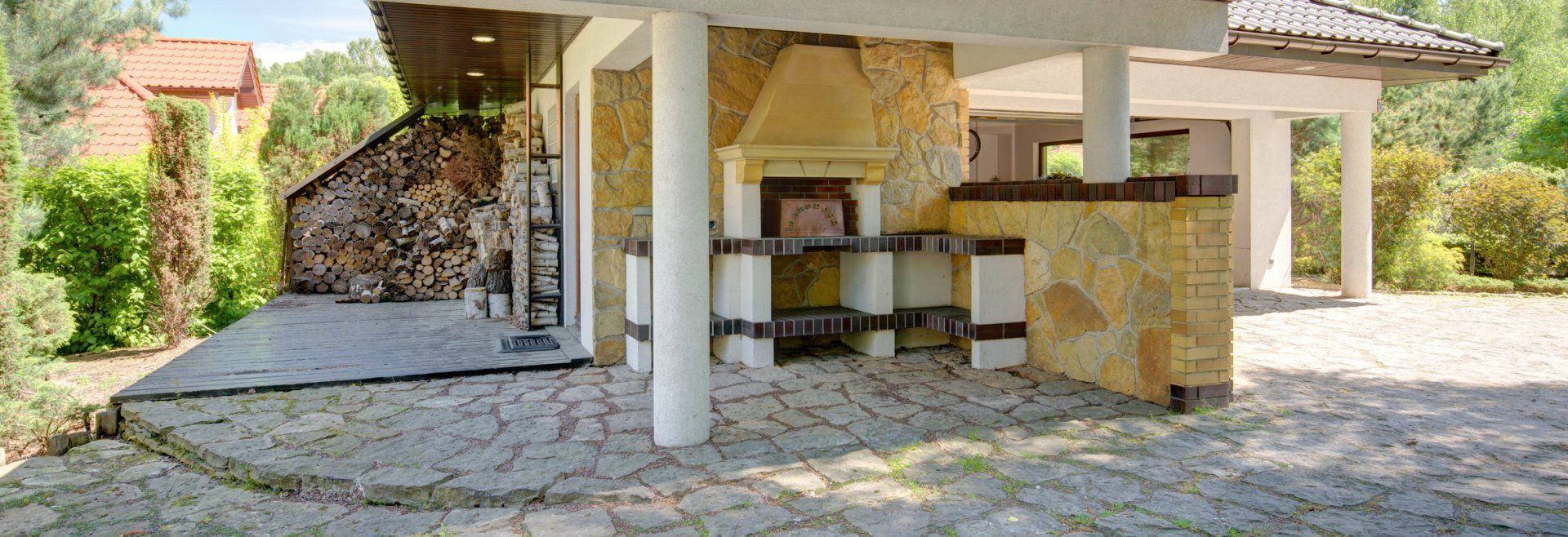 A stone building with a grill and a covered patio in front of it.