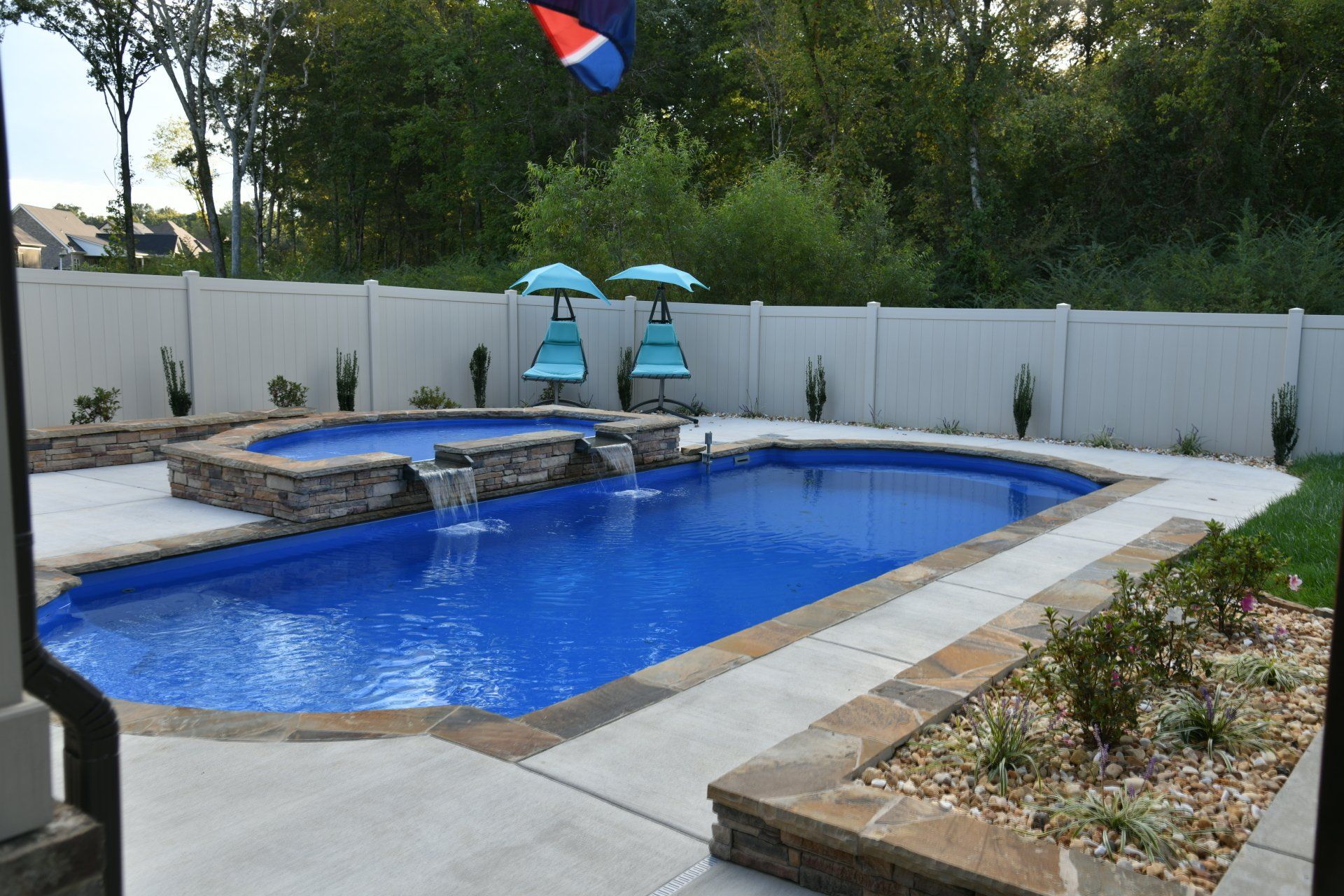 A large swimming pool is surrounded by a white fence.