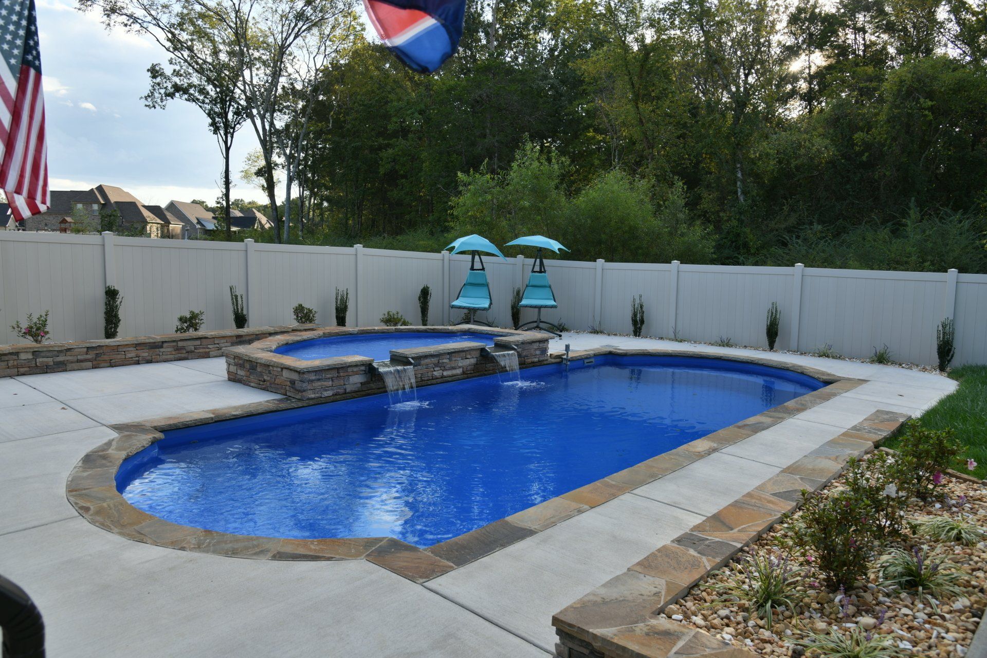 A large swimming pool with umbrellas and a flag in the background