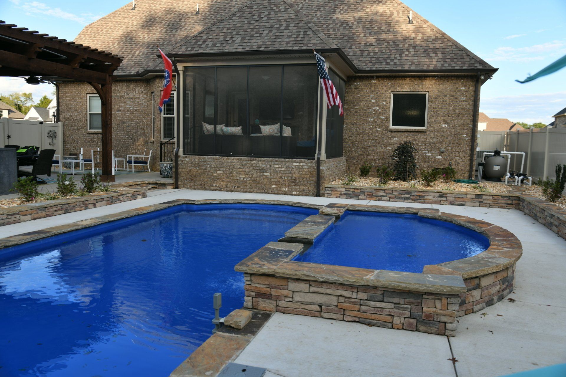 A large swimming pool in front of a house with a screened in porch.