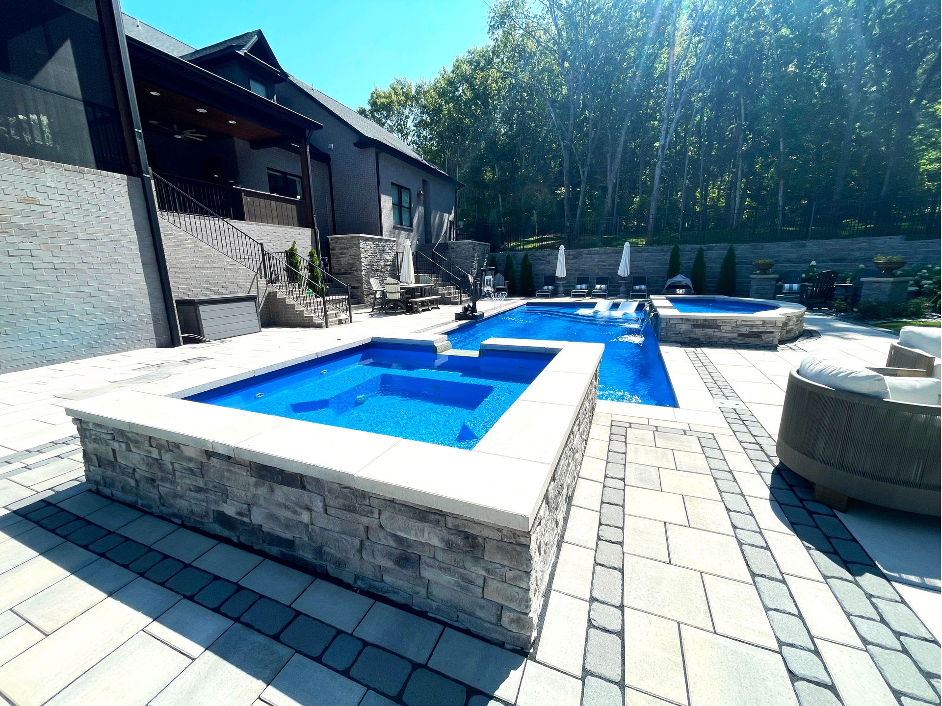 Stunning Aspen pool featuring a 9 sq ft spillover spa and elegant stone patio in Murfreesboro, Tennessee.