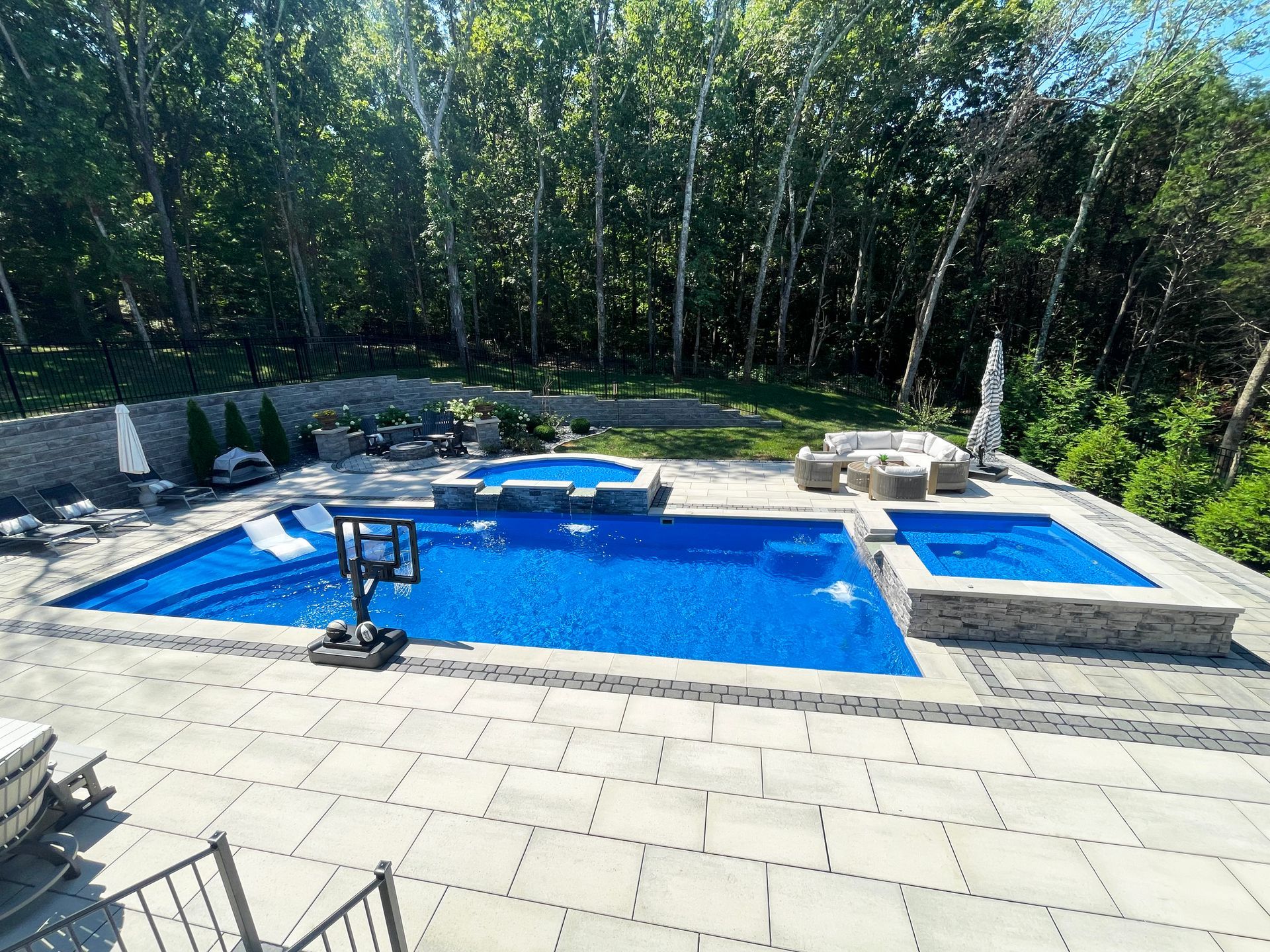 Majestic Swim backyard pool design with retaining walls, fire pit, and lounge space in Murfreesboro, Tennessee.