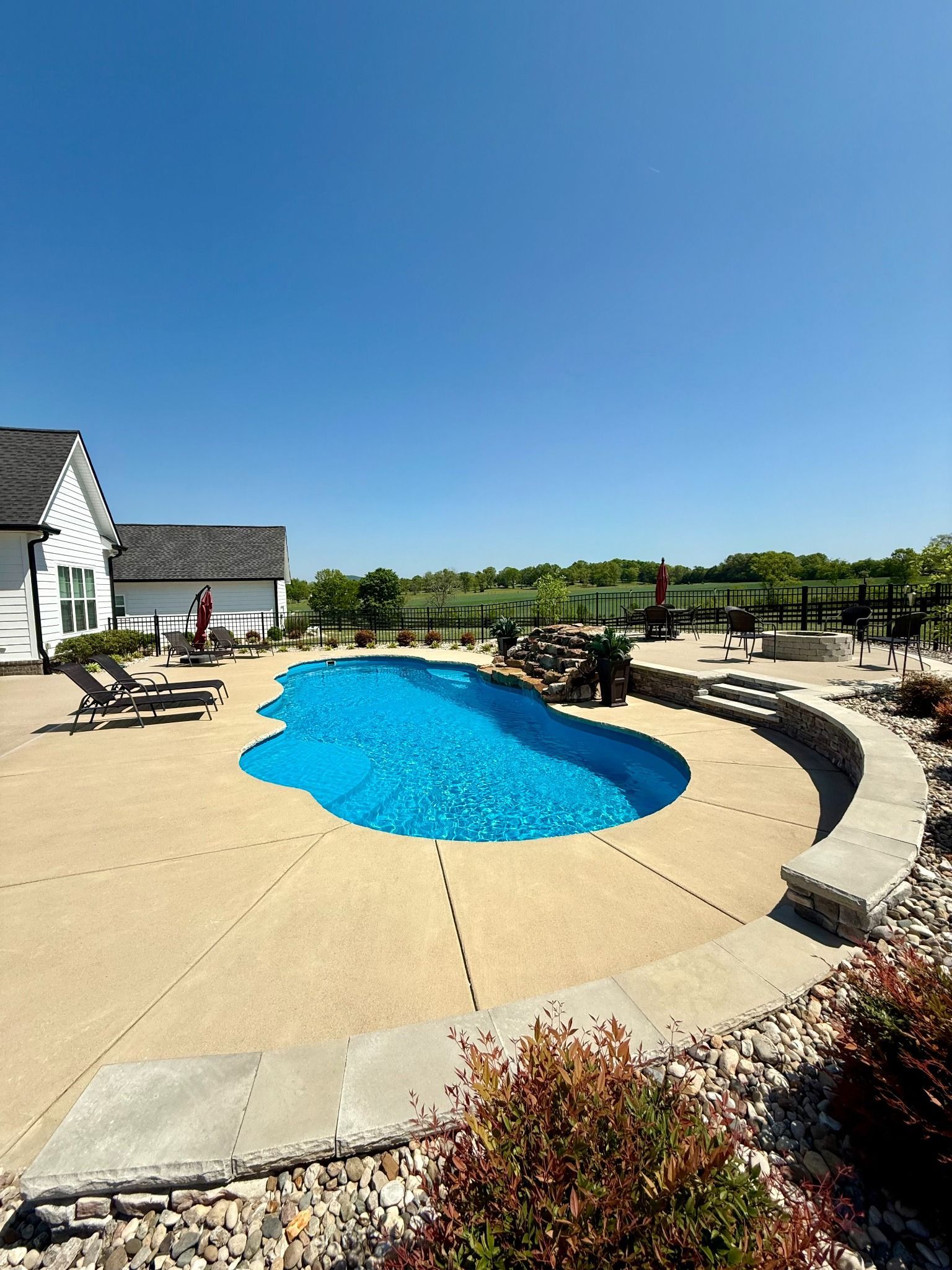 Curved entry steps leading into Aspen 16x35 fiberglass pool with seating area