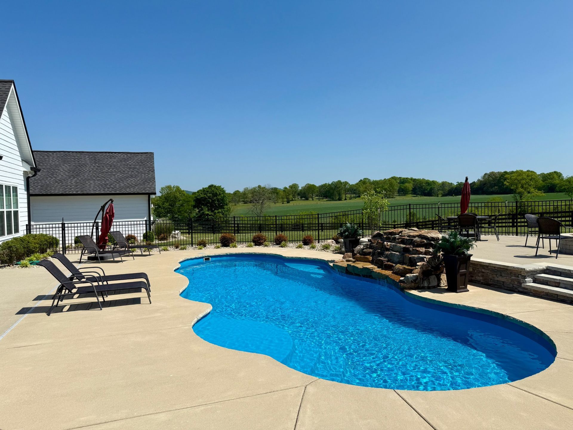Backyard pool and patio area overlooking green fields in Lascassas, TN
