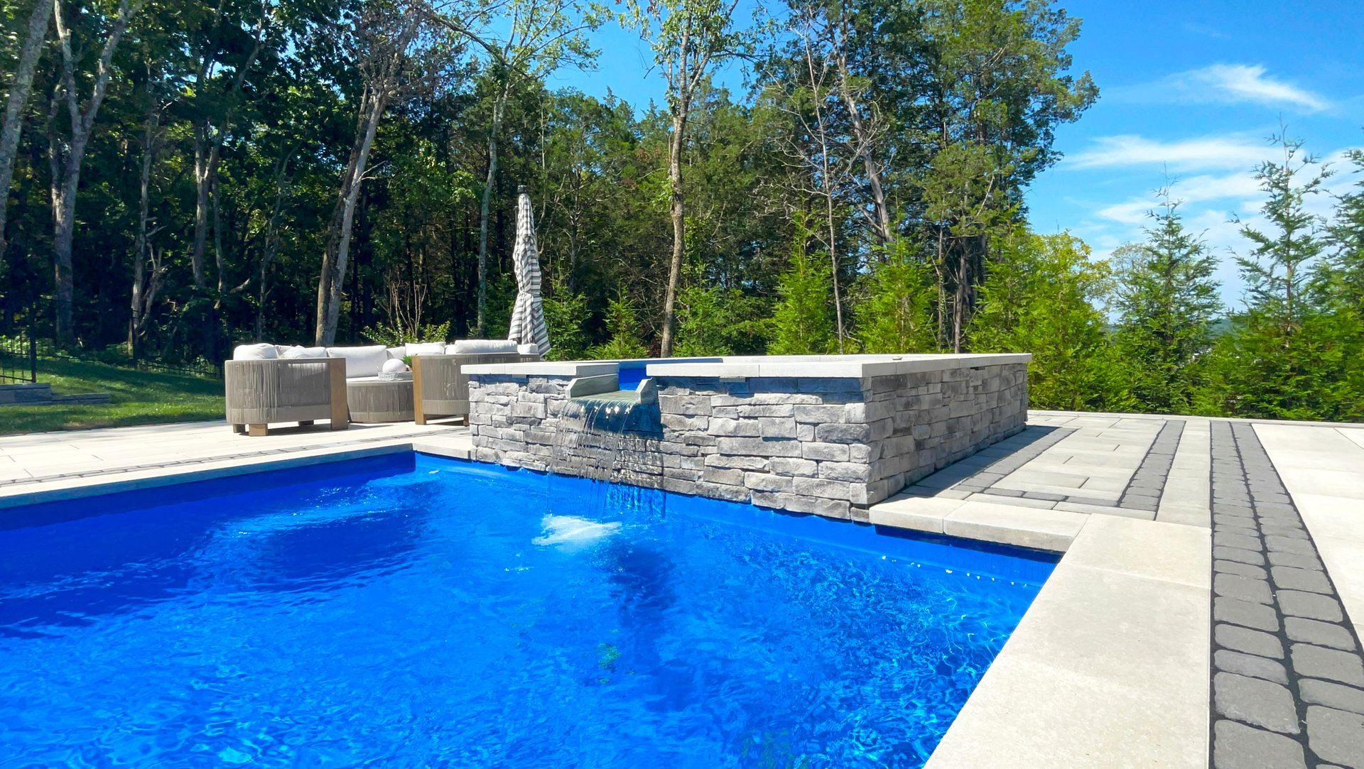 Elegant spillover hot tub with stone surround pouring into an Aspen pool in Murfreesboro, TN.