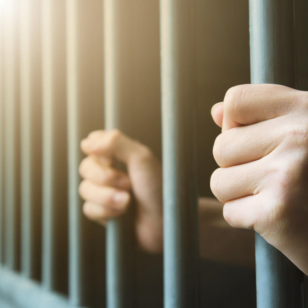Hands holding jail cell