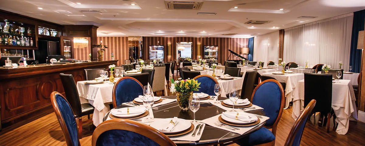 Uma grande sala de jantar com mesas e cadeiras e um bar.