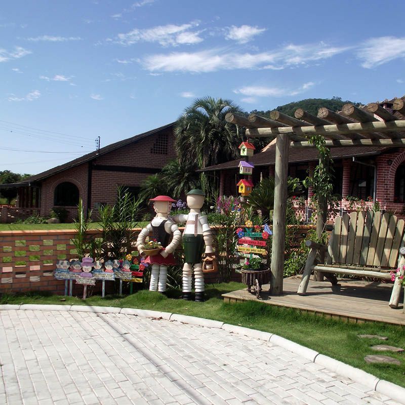 Jardim temático com esculturas de jardineiros e casinha de pássaros.