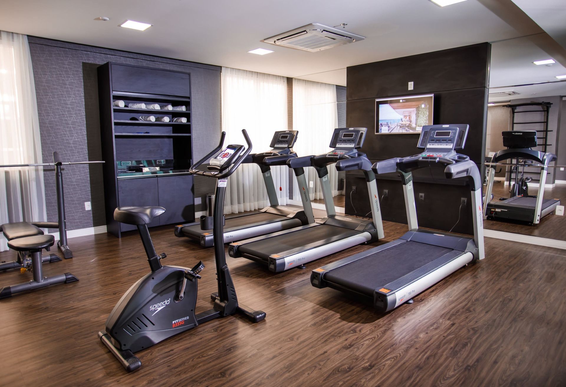 Uma academia com esteiras, bicicleta e televisão.