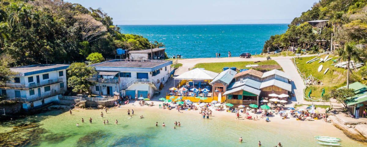 Vista aérea de uma praia com muita gente nadando na água.