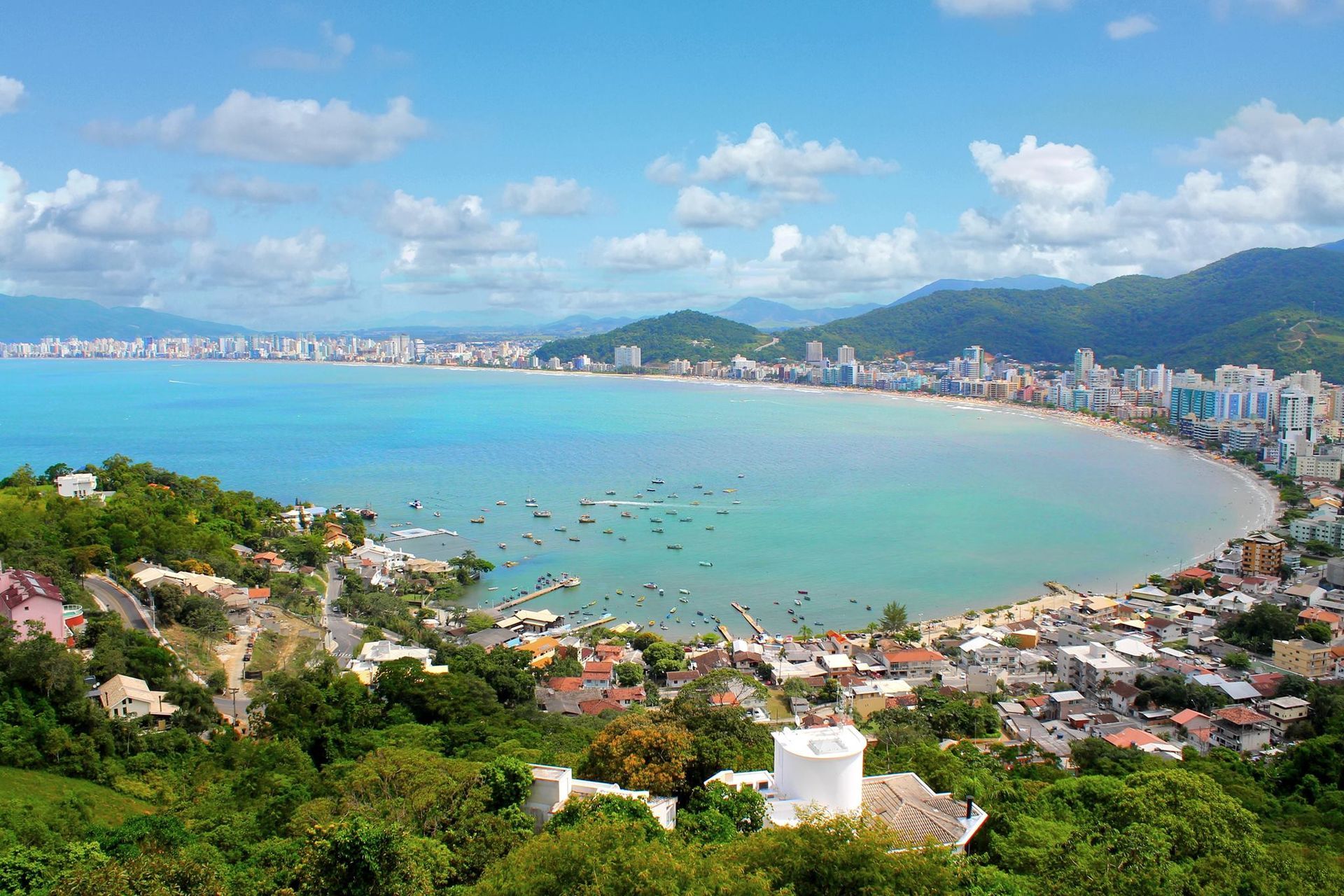 Vista aérea de uma praia com uma cidade ao fundo.