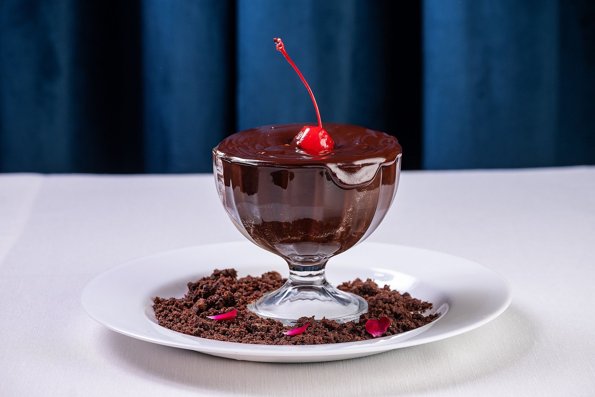Uma tigela de pudim de chocolate com uma cereja em cima de um prato.