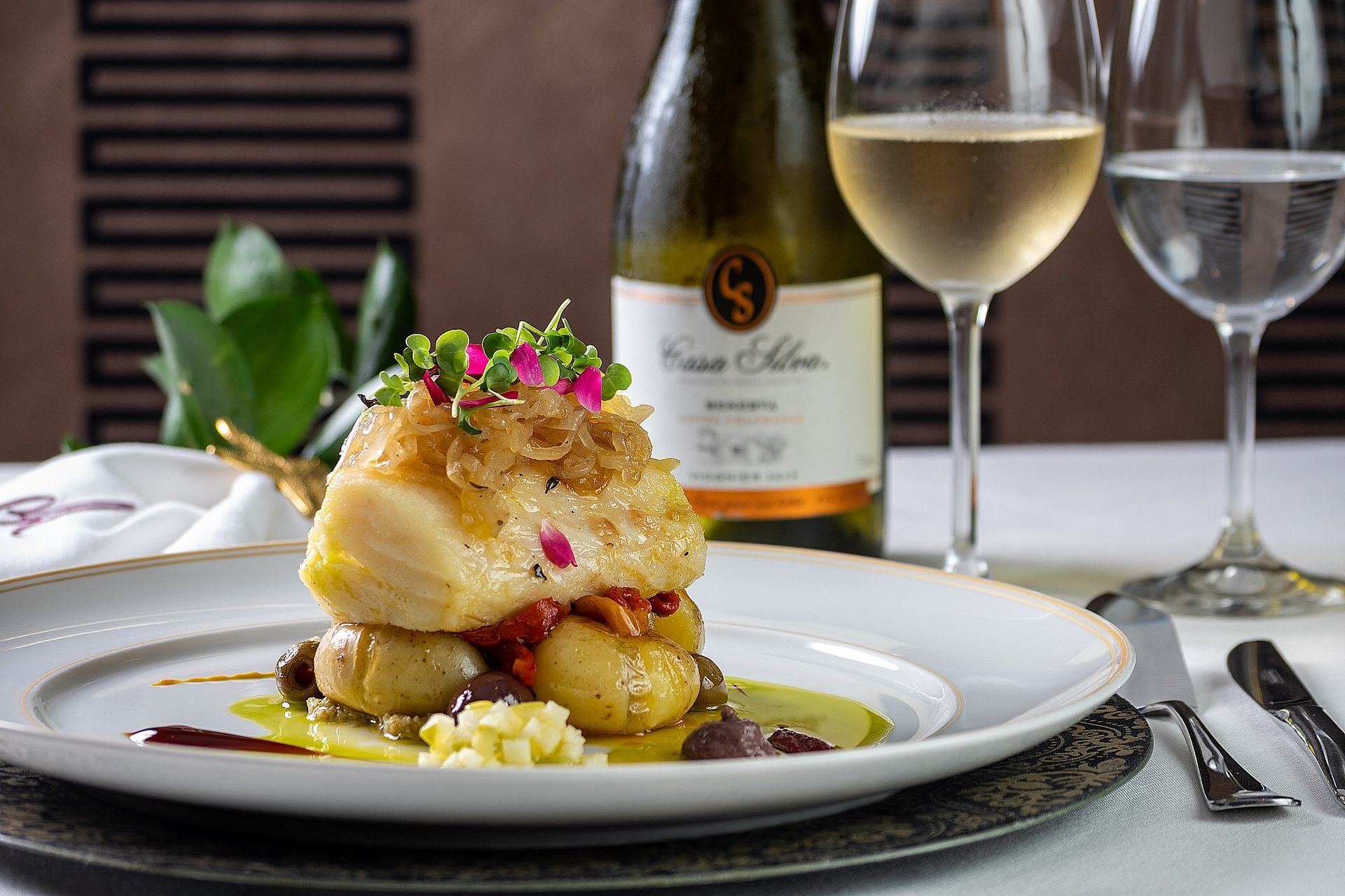 Um prato de comida com uma garrafa de vinho ao fundo
