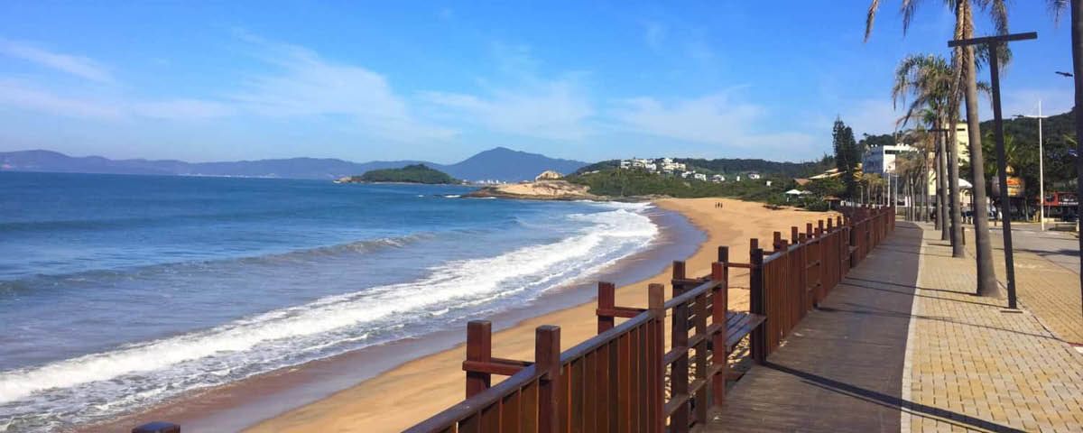 Uma cerca de madeira ao longo de uma praia com vista para o oceano.