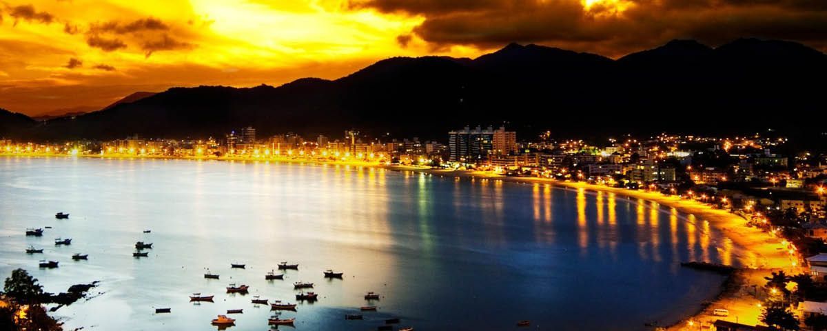 Um pôr do sol sobre um corpo de água com uma cidade ao fundo.