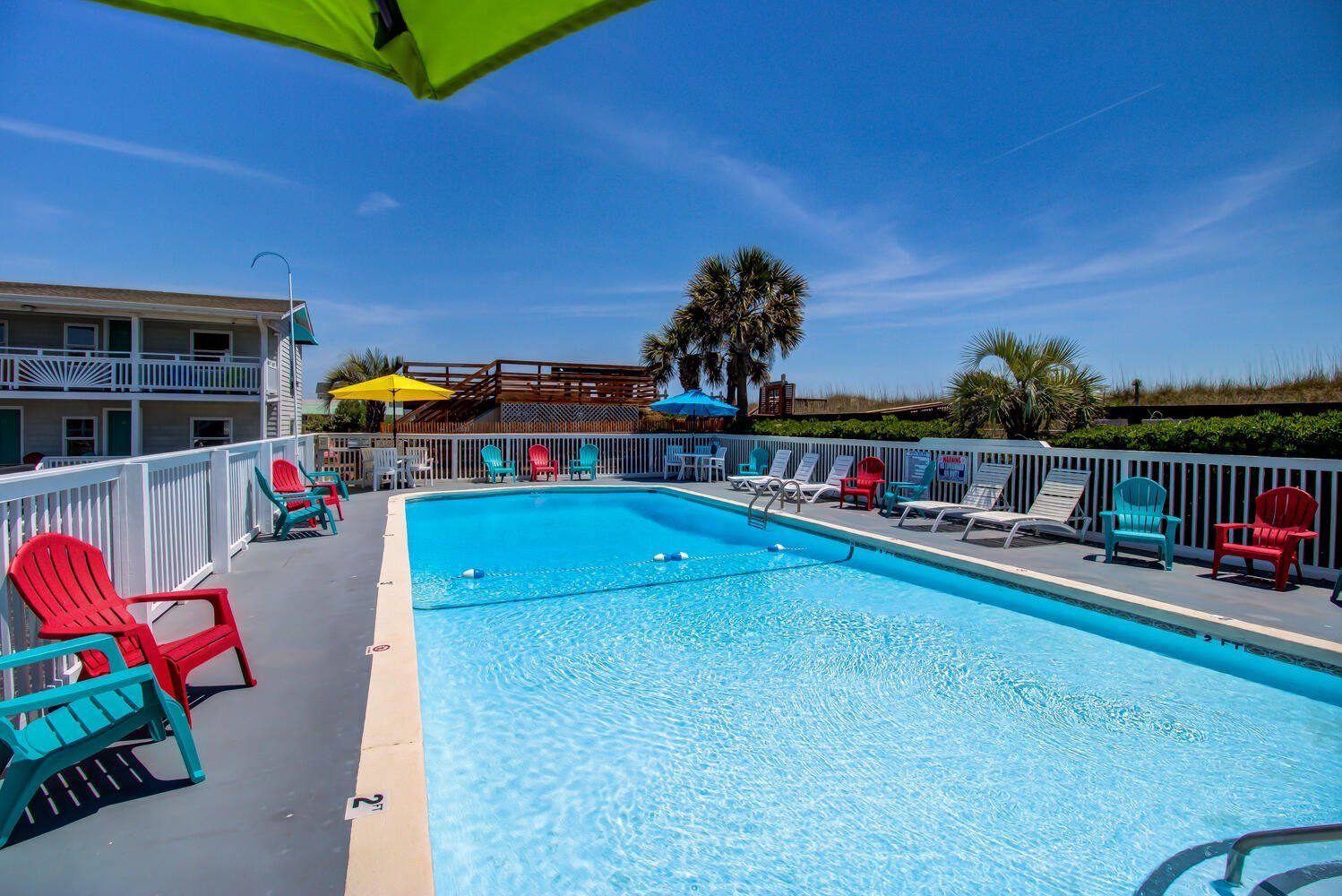 A large swimming pool surrounded by chairs and umbrellas.