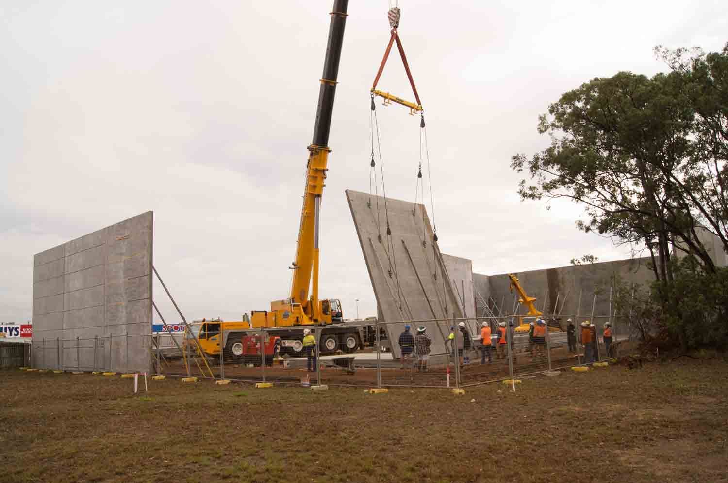 A Crane Lifts a Concrete Wall Panel at A Construction Site — Wieland Concreting in Rockhampton, QLD