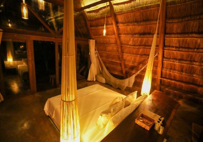 Habitación cálida iluminada con velas, con cama con dosel y paredes rústicas de madera.
