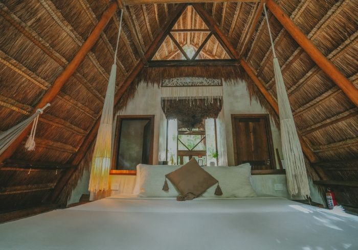 Un acogedor dormitorio abuhardillado con techo a dos aguas de paja, cama y un cálido interior de madera.
