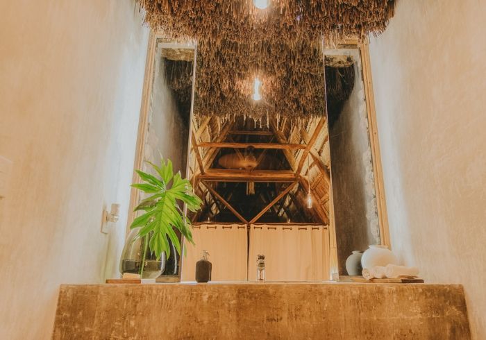 Rellano de escalera interior con iluminación cálida, plantas colgantes, una planta en maceta y escalones de madera.