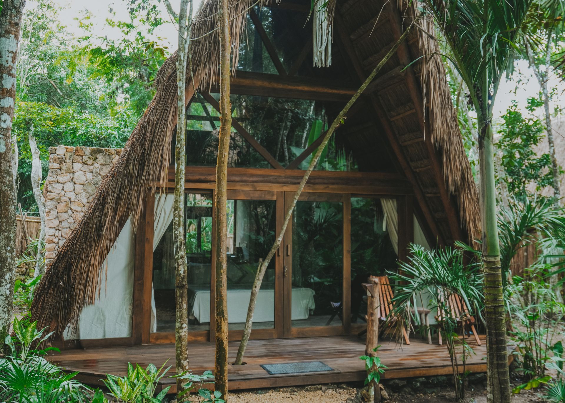Una pequeña cabaña con techo a dos aguas y techo de paja, enclavada entre árboles tropicales y vegetación.