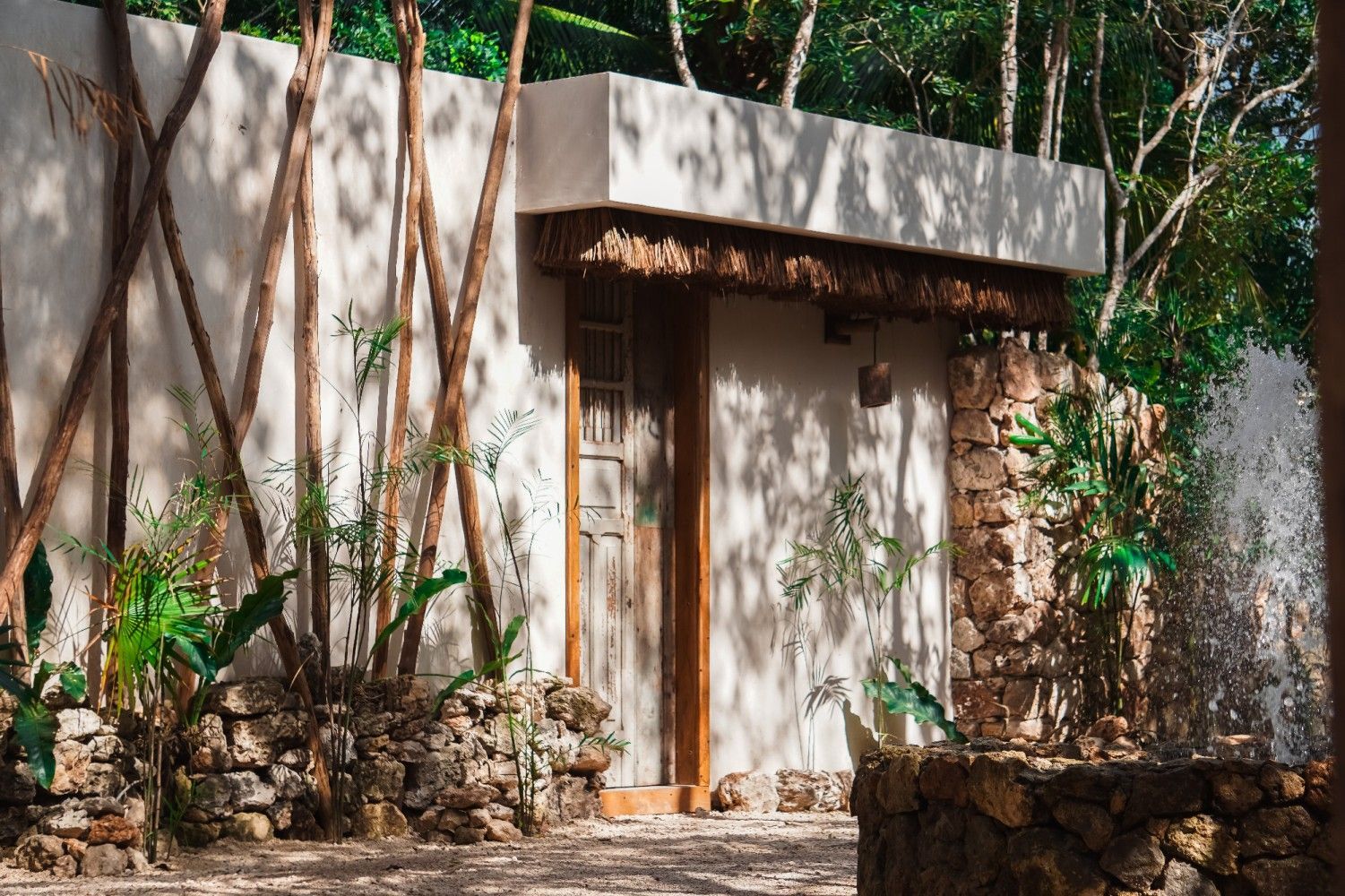Pequeña construcción de piedra con puerta de madera en un entorno boscoso al aire libre.