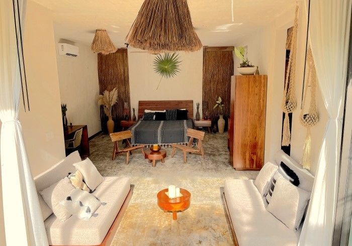 Acogedora sala de estar con sofás blancos, lámparas colgantes de mimbre, una mesa de comedor y decoración de madera cálida.