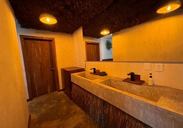 Baño en tonos cálidos con lavabos dobles, puertas de madera y luces de techo redondas.