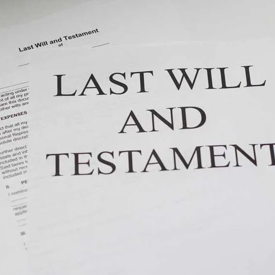 Close-up of a last will and testament document on a table, with large black serif text.