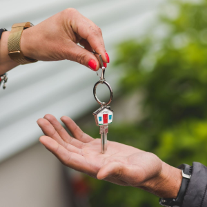 Handing over a house key to an outstretched hand outdoors