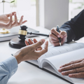Hands signing a document in a law office with a gavel on the table