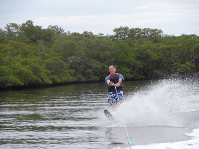 A man is water skiing on a lake with trees in the background.