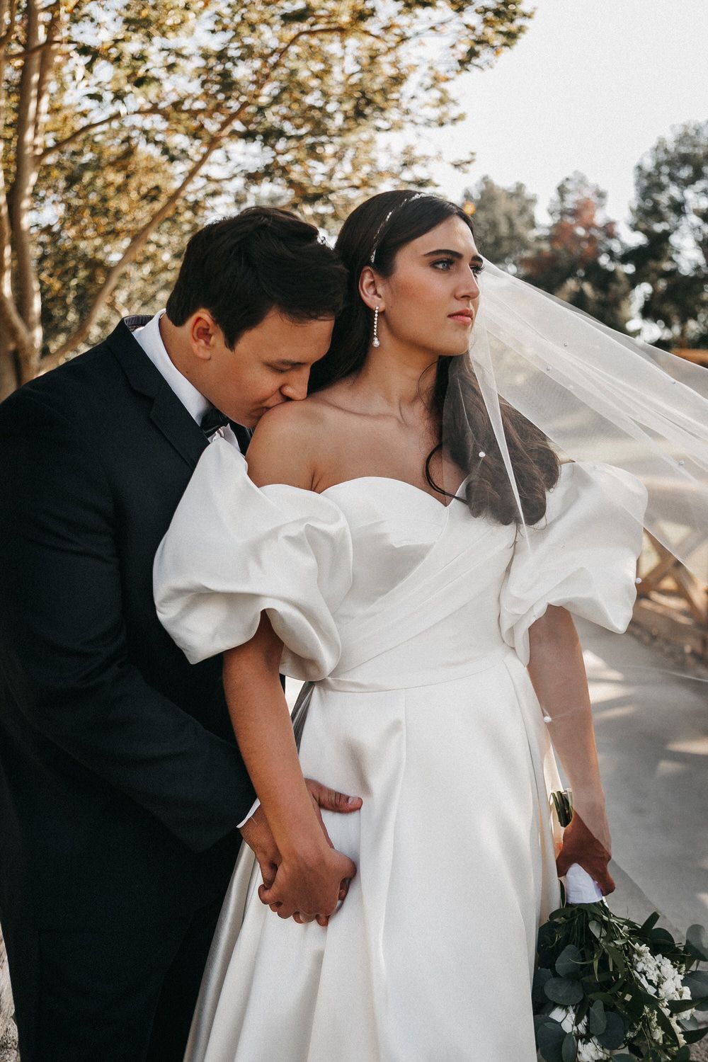A bride and groom are posing for a picture and the bride is wearing a veil. Orange county hair and makeup artist.