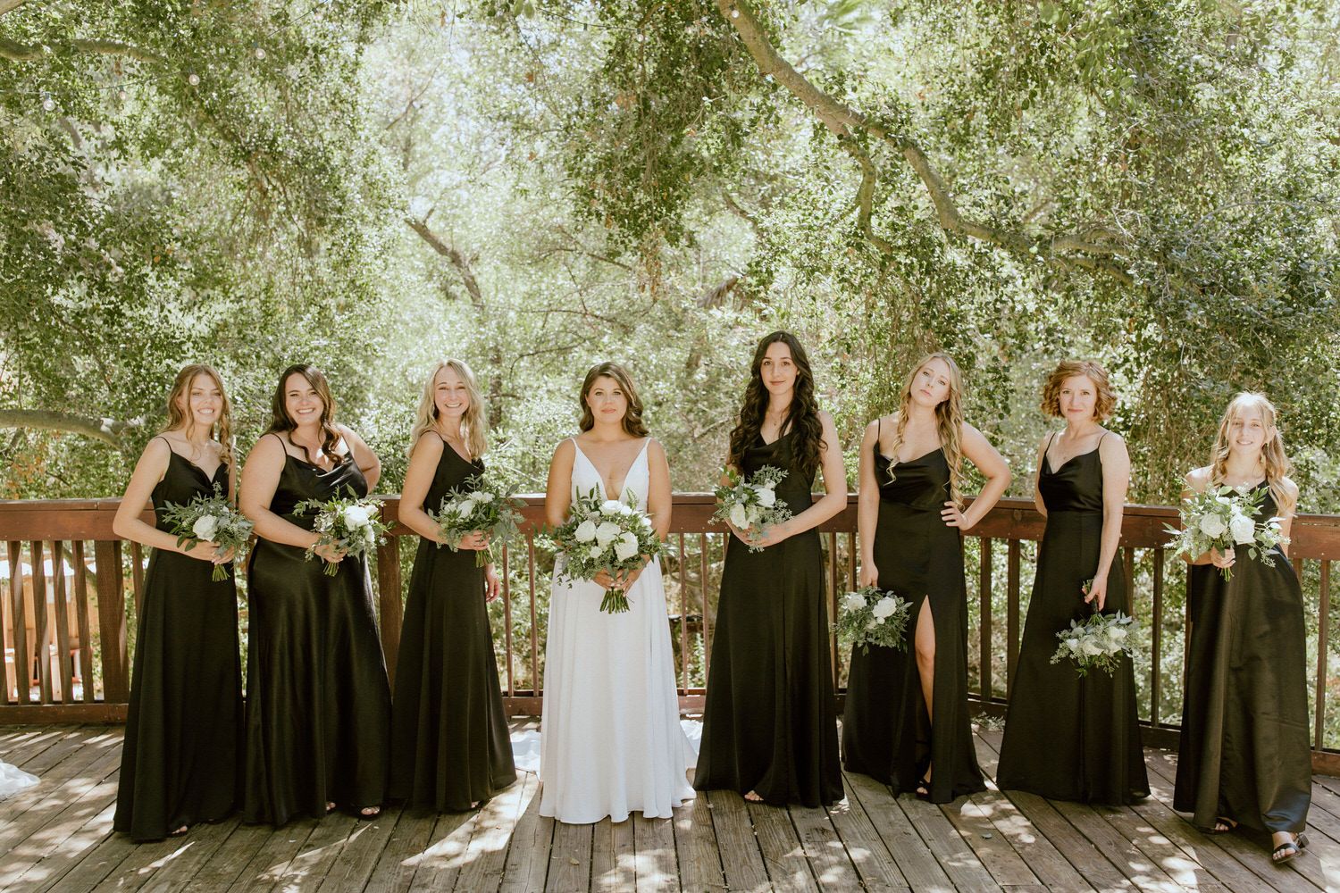 A bride and her bridesmaids are posing for a picture on a deck. Orange county hair and makeup artist.