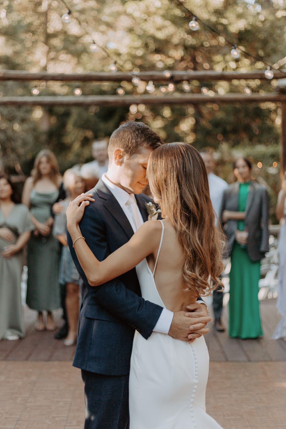 A bride and groom are kissing during their first dance at their wedding . Orange county hair and makeup artist.reception.