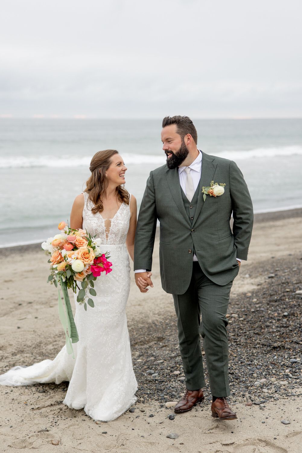 A bride and groom are walking on the beach holding hands. Orange county hair and makeup artist.