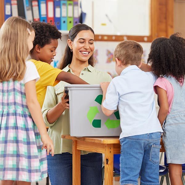 Teacher with children around a recycling bin in a classroom