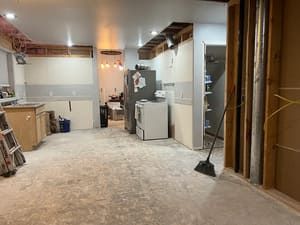 A kitchen under construction with a broom in the middle of the room.