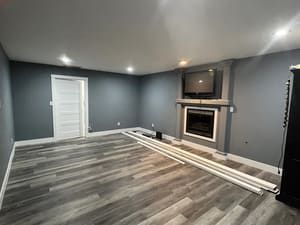 A living room with a fireplace and a television on the wall.