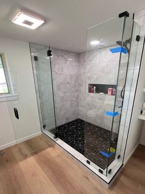 A bathroom with a walk in shower with a glass door.