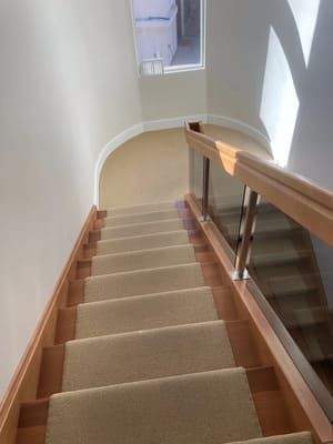 A wooden staircase with a carpeted staircase and a glass railing.