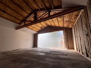 A large empty room with a wooden ceiling and a sliding glass door.